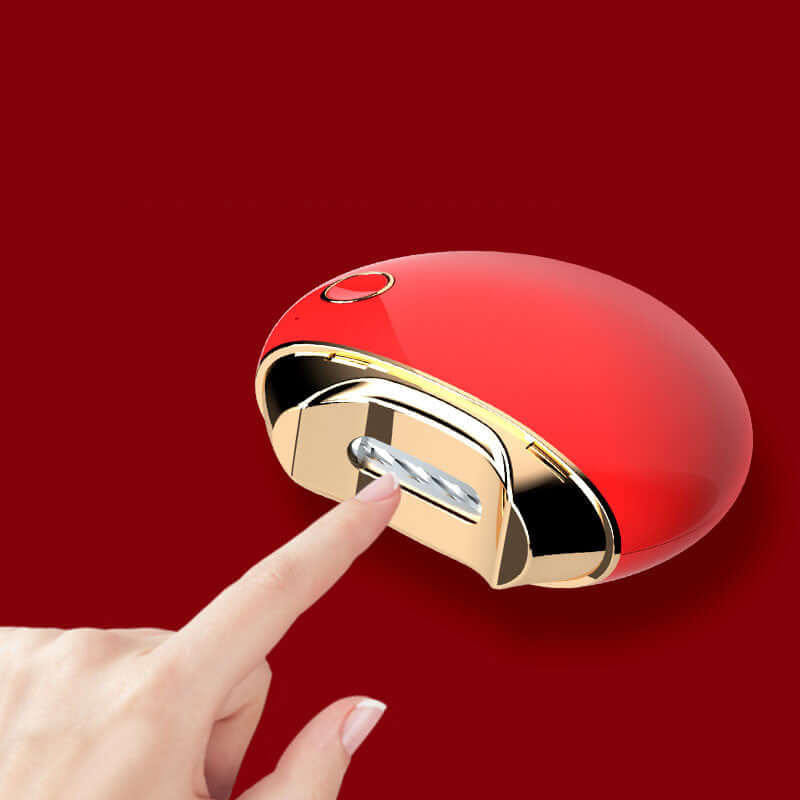 Red electric nail clippers with gold accents, shown in use as a finger presses the button for easy nail trimming.
